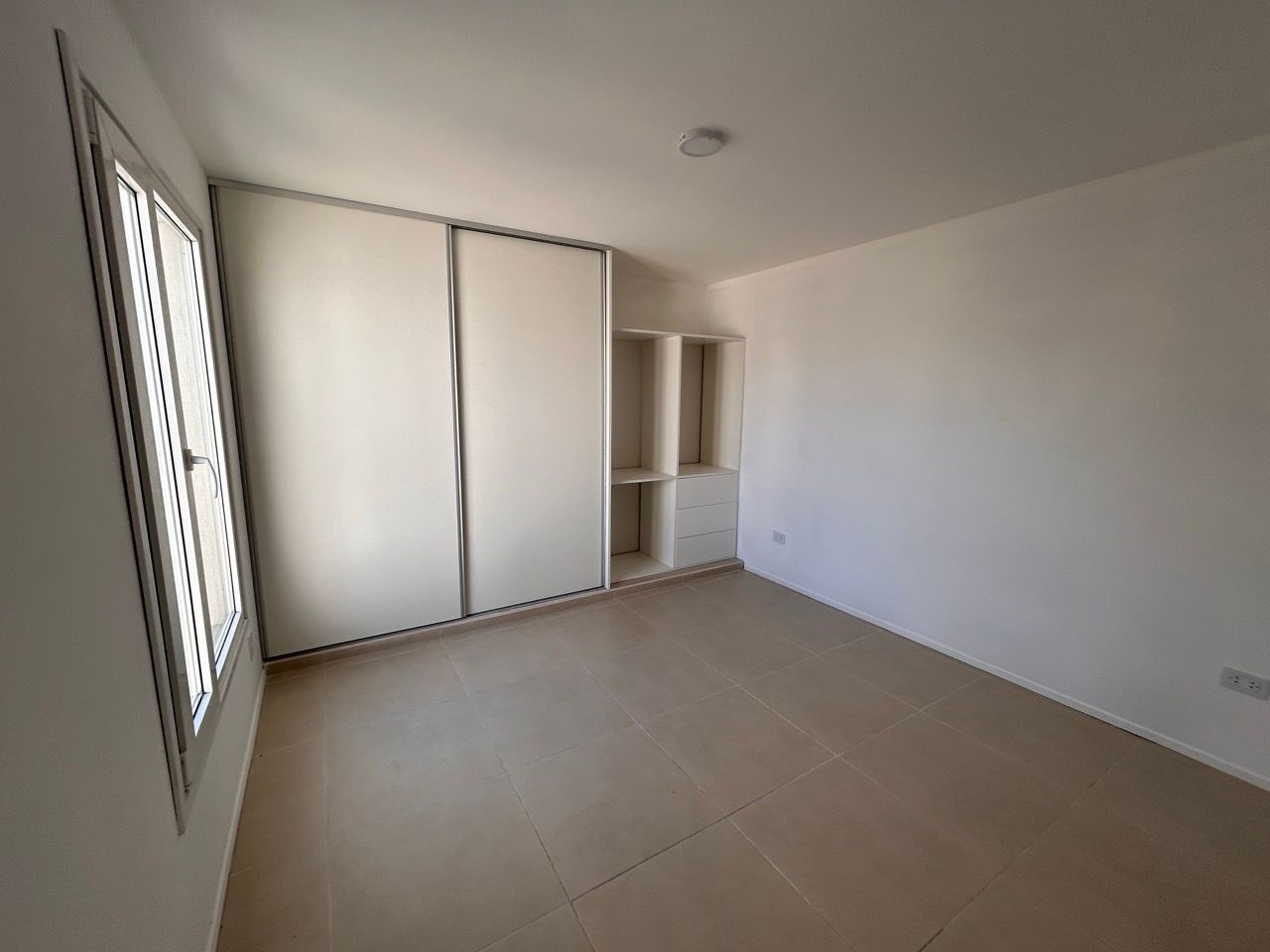 Dormitorio con placard corredizo blanco y ventana